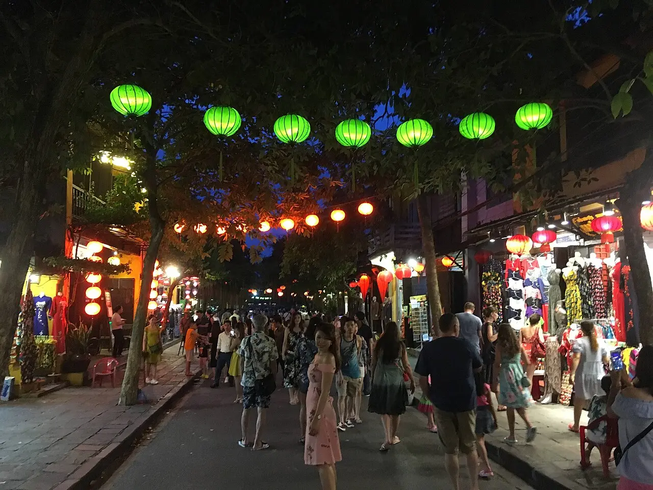 Con phố về đêm treo dây đèn lồng xanh và đỏ, hai bên cửa hàng sáng đèn, du khách đi bộ