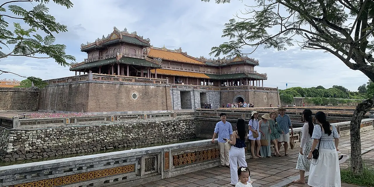 Lầu Ngũ Phụng mái ngói vàng trên nền thành đá của Ngọ Môn, du khách đứng trên cầu phía trước